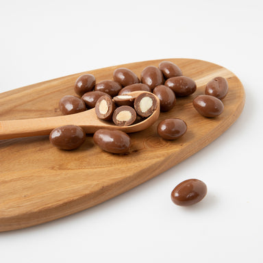 Delicious Milk Chocolate Almonds (Chocolates) on wooden serving board - Naked Foods