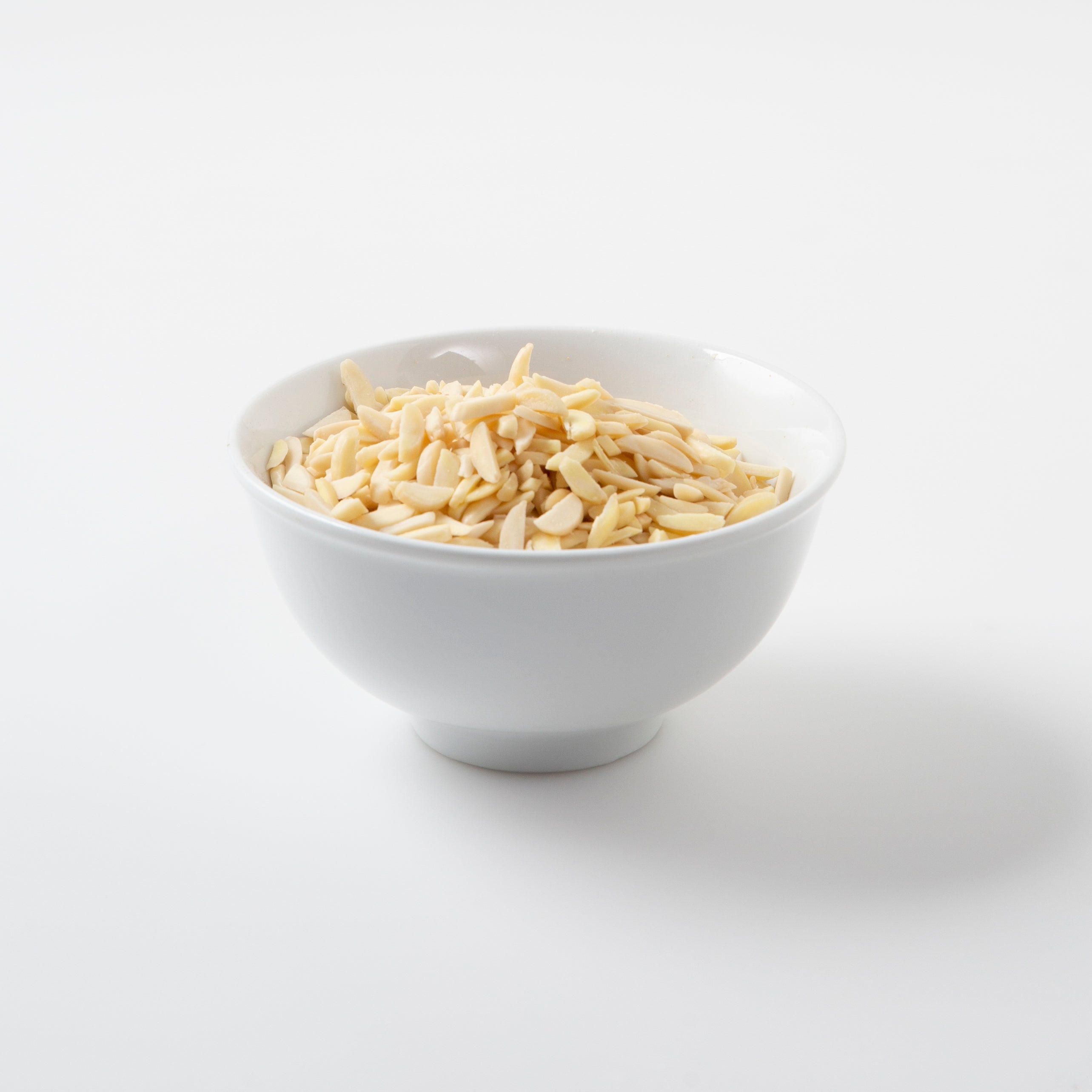 Blanched Slivered Almonds (Raw Nuts) in white bowl - Naked Foods