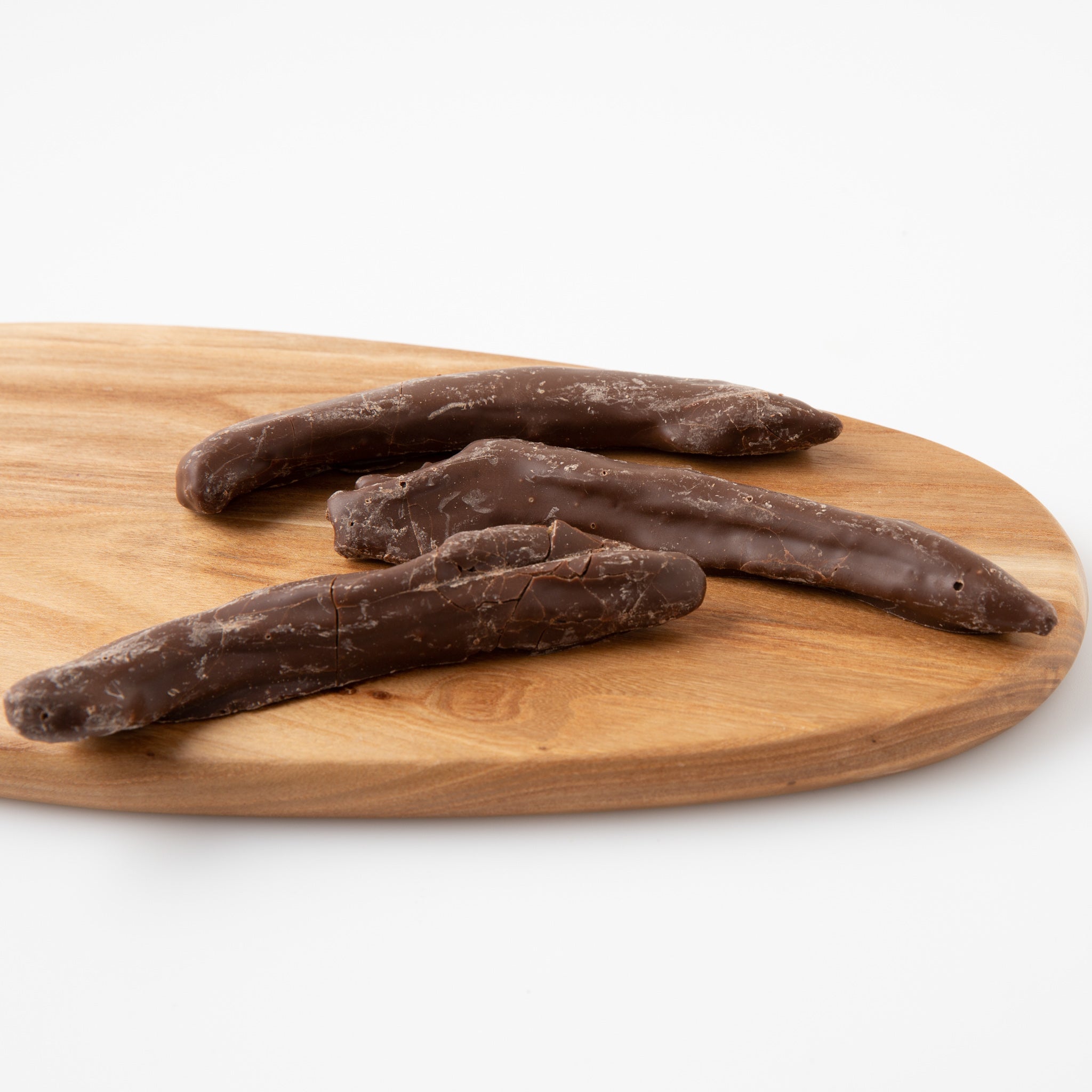 A close up photo Carob Coated Bananas (Carob) on wooden serving board - Naked Foods
